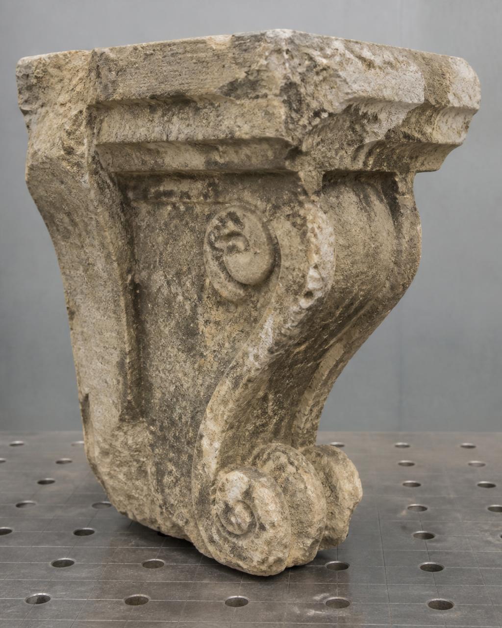 Weathered 19th-century architectural corbel awaiting restoration